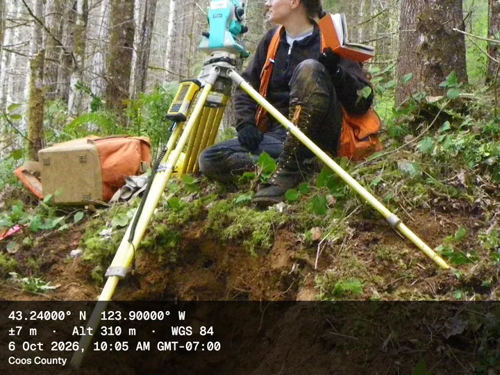 Surveyor with a total station in a forest, with the Survey stamp: coordinates first, ±7 m accuracy, altitude 310 m, WGS 84, Coos County, Oregon
